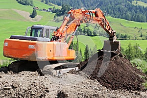 Orange mechanical digger working on a field