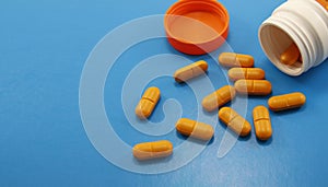 Orange medical pills and tablets spilling out of a drug bottle