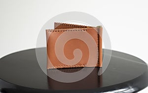 Orange men's money clip handmade leather wallet with a two pockets on a black table.