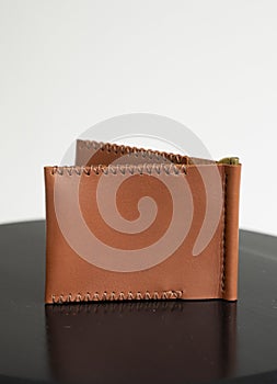 Orange men's money clip handmade leather wallet with a two pockets on a black table.