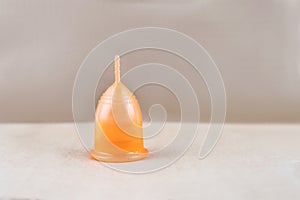 Orange menstrual cup on a craft paper background.