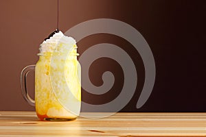 Orange milkshake with chocolate pouring. banan milkshake dessert with orange pasta on wooden table