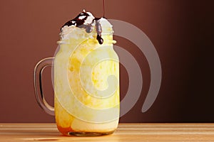 Orange milkshake with chocolate pouring. banan milkshake dessert with orange pasta on wooden table