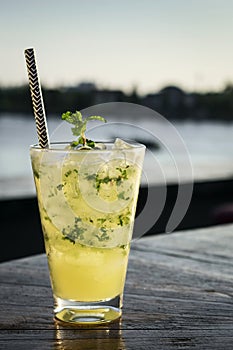 Orange mojito summer cocktail drink in outdoor riverside bar