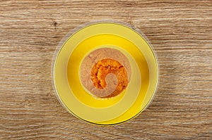 Orange muffin in saucer on brown wooden table