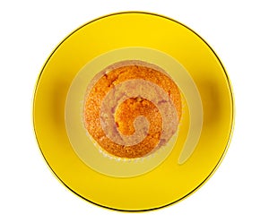 Orange muffin in yellow saucer isolated on white. Top view