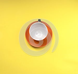 Orange mug with coffee isolated on a yellow background