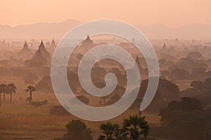 Orange mystical sunrise landscape view with silhouettes of old ancient temples and palm trees in dawn fog from balloon