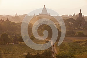 Orange mystical sunrise landscape view with silhouettes of old ancient temples and palm trees in dawn fog from balloon