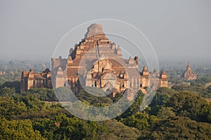 Orange mystical sunrise landscape view with silhouettes of old ancient temples and palm trees in dawn fog from balloon