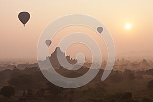 Orange mystical sunrise landscape view with silhouettes of old ancient temples and palm trees in dawn fog from balloon