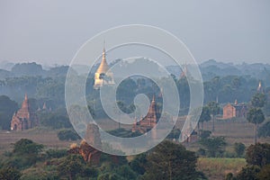 Orange mystical sunrise landscape view with silhouettes of old ancient temples and palm trees in dawn fog from balloon