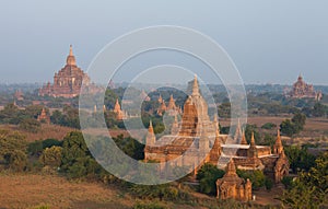 Orange mystical sunrise landscape view with silhouettes of old ancient temples and palm trees in dawn fog from balloon