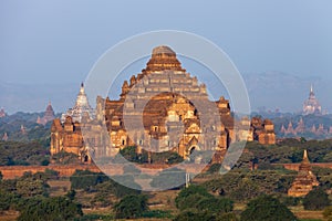 Orange mystical sunrise landscape view with silhouettes of old ancient temples and palm trees in dawn fog from balloon