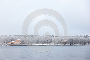 Orange Nedre Manilla building in snow covered Stockholm island of DjurgÃ¥rden in winter fog photo