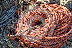 Orange Nylon rope coiled and ready for use on a working dock