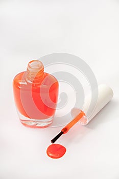 The orange opened nail varnish with spilled on a white background