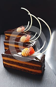 Orange Opera cake slices with citrus ganache and white chocolate decorations