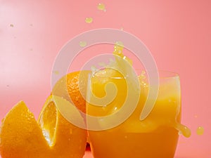 Orange and orange slice. Orange Juice Splashing. Orange on a pink background.