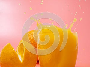 Orange and orange slice. Orange Juice Splashing. Orange on a pink background.