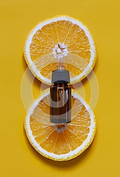 Orange organic aromatic oil in a glass bottle with a pipette on a background of fresh orange slices