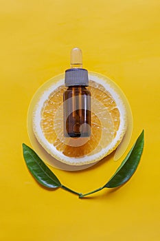 Orange organic aromatic oil in a glass bottle with a pipette on a background of fresh orange slices