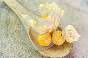 Orange Organic Cape Gooseberries in a wooden spoon
