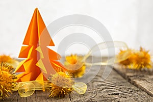 Orange origami tree with shiny balls on a wooden base with a white background.