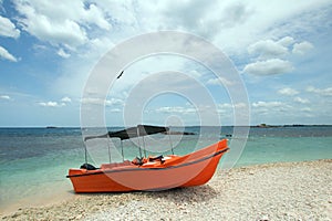 Orange panga / fishing boat on coral beach in Sri Lanka photo