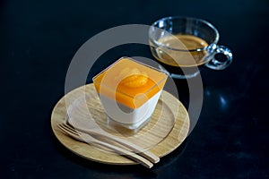 Orange panna cotta on  wooden dish with black background