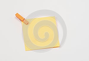 Orange paper notes fastened with a wooden clothespin on a white background