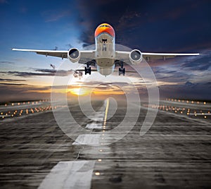 Orange passenger plane takes off from the airport runway during the sunset