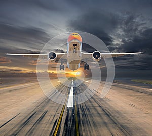 Orange passenger plane takes off from the airport runway during the sunset. Front view