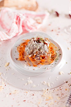 Orange pasta and white sauce served on white plate