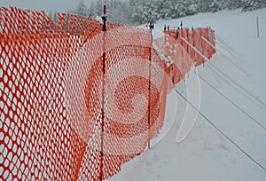 Orange perforated plastic PE foil barriers against snow in mountain areas. slow down the speed of snow, forming tongues and dune b