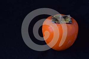An orange persimmon on a black background