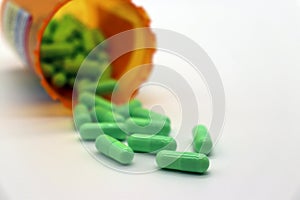 Orange pill bottle of green capsules