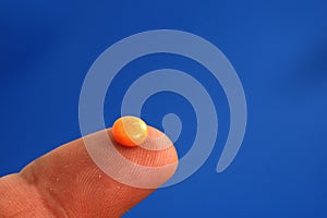 Orange pill on a finger