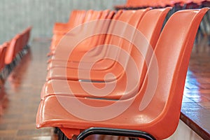 Orange plastic chairs lined up, seen in profile