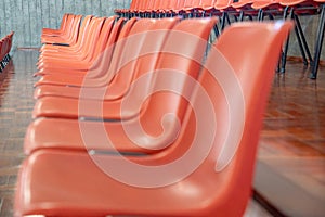 Orange plastic chairs lined up, seen in profile