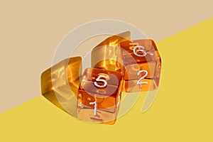 Orange plastic dice on a yellow background with the winning come out roll corresponding to a die with the number 5 and a die with