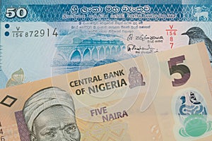 A orange, plastic five naira note from Nigeria paired with a blue and white fifty rupee bank note from Sri Lanka.