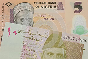 A orange, plastic five naira note from Nigeria paired with a pink and grey ten rupee note from Pakistan.