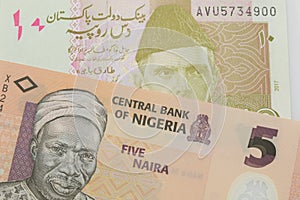 A orange, plastic five naira note from Nigeria paired with a pink and grey ten rupee note from Pakistan.