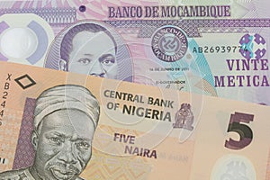 A orange, plastic five naira note from Nigeria paired with a purple, plastic twenty metical note from Mozambique.