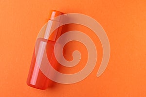 An orange plastic flacon bottle on the orange background