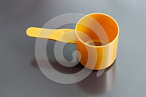 Orange plastic measuring dosage spoon on dark background photo