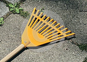 orange plastic rake lying on stone slabs in the backyard