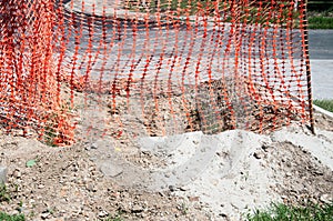 Orange plastic safety net or barrier on the street to protect excavating construction site close up