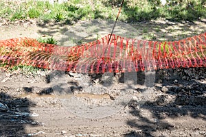 Orange plastic safety net or barrier on the street to protect excavating construction site close up